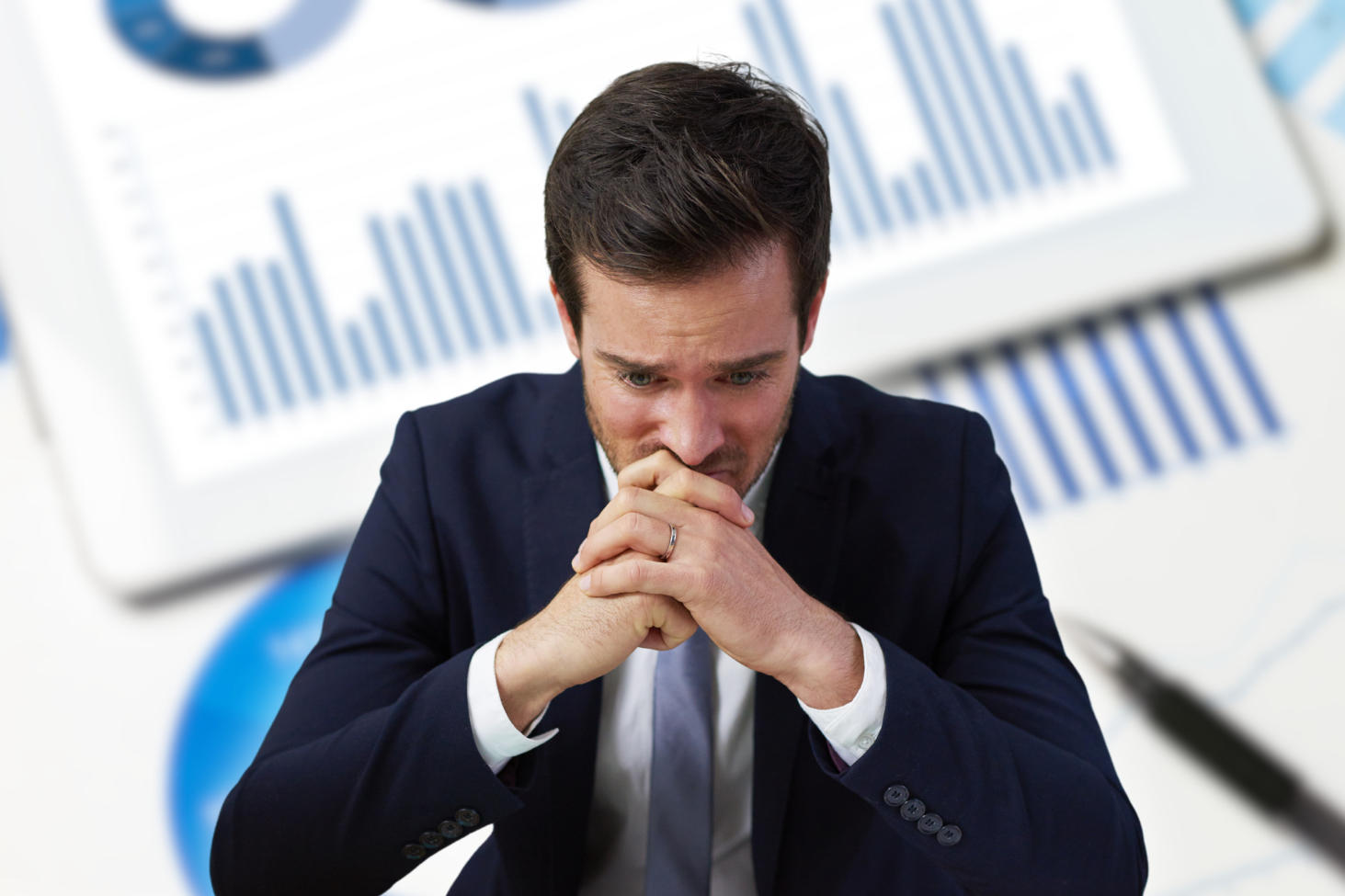 Na zdjęciu widzimy załamanego mężczyznę na tle wykresu.