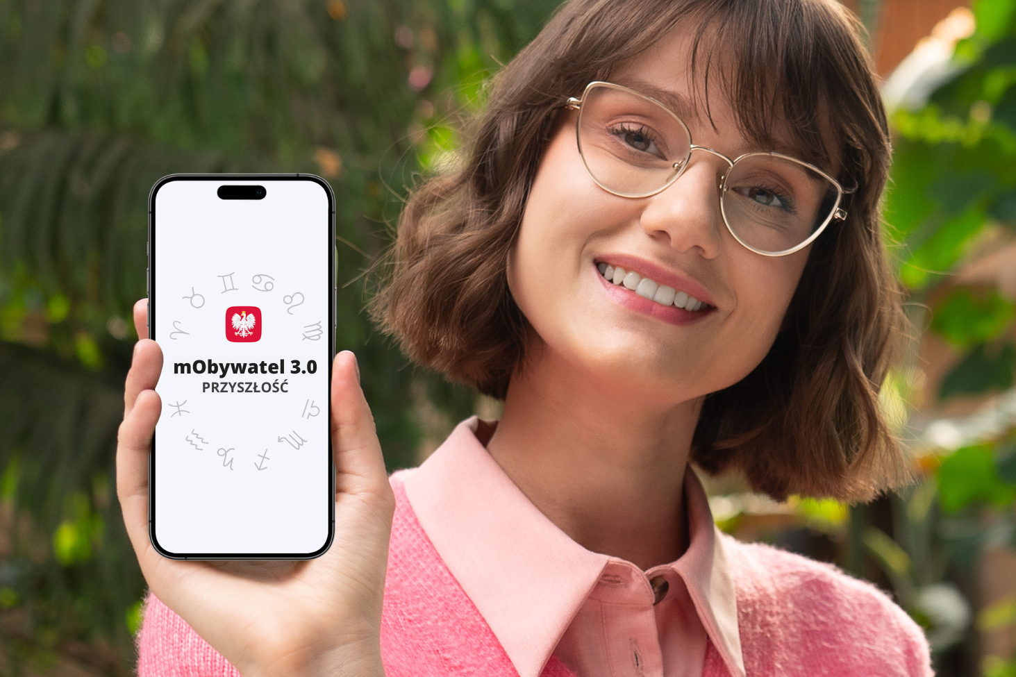 Na zdjęciu widzimy kobietę trzymającą telefon z otwartą aplikacją mObywatel.